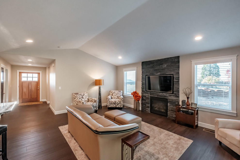 Exemple d'une salle de séjour tendance ouverte avec un mur beige, une cheminée standard, un manteau de cheminée en pierre, un sol marron et un téléviseur fixé au mur.
