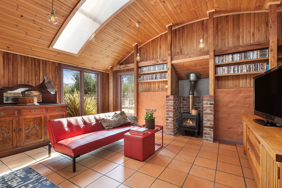 Immagine di un soggiorno stile marinaro chiuso con pavimento in terracotta, camino classico e TV autoportante