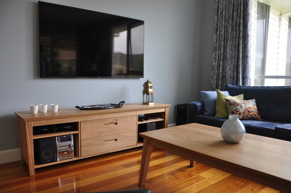 Foto de sala de estar abierta actual de tamaño medio con paredes azules, suelo de madera en tonos medios, televisor colgado en la pared y suelo marrón