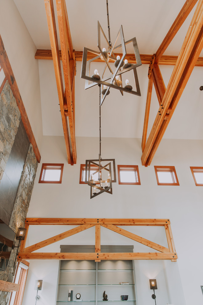 Modelo de sala de estar tipo loft tradicional renovada extra grande con paredes grises, suelo de madera en tonos medios, todas las chimeneas, marco de chimenea de piedra y televisor colgado en la pared