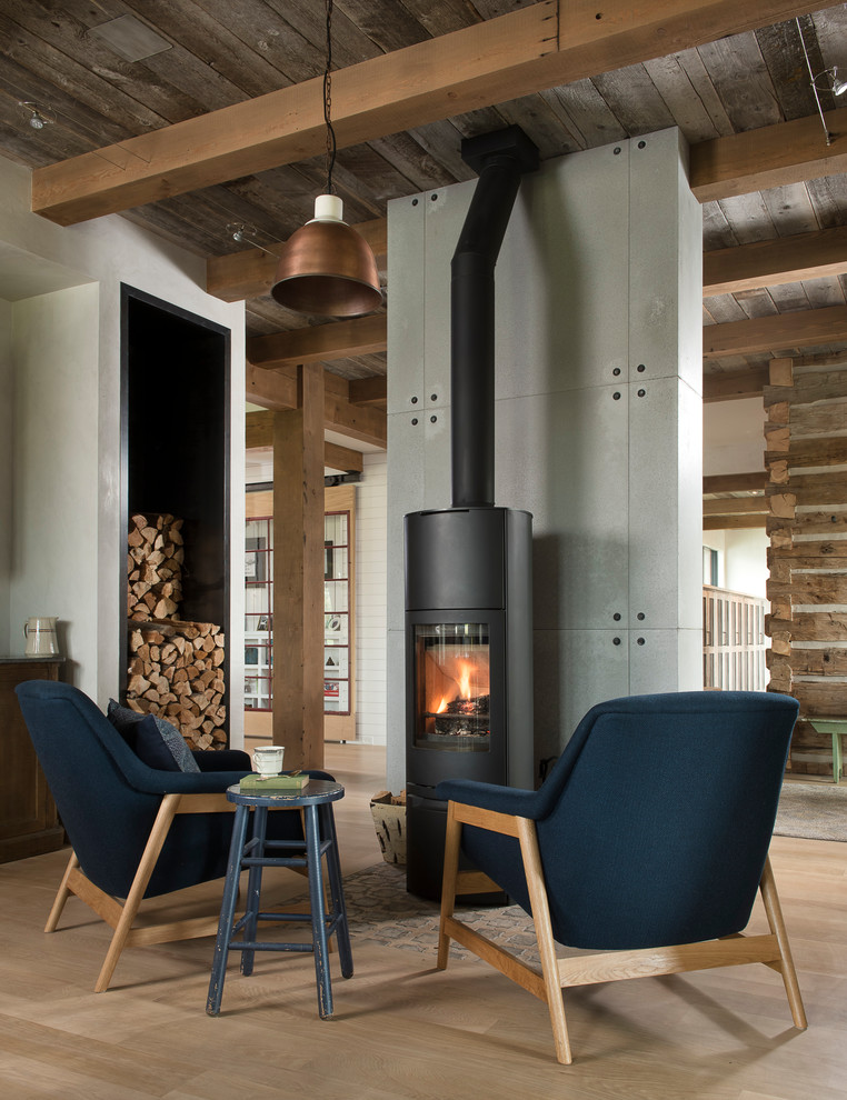 Small farmhouse open plan games room in Other with grey walls, light hardwood flooring, a wood burning stove, a concrete fireplace surround and no tv.