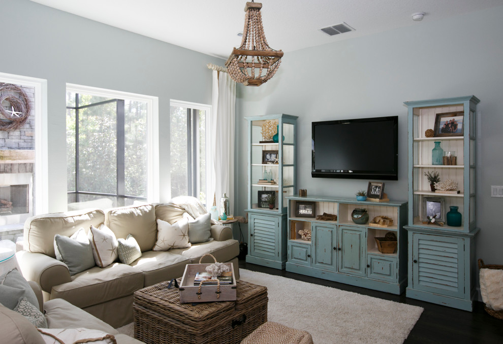 На фото: открытая гостиная комната среднего размера в морском стиле с синими стенами, темным паркетным полом, телевизором на стене и коричневым полом