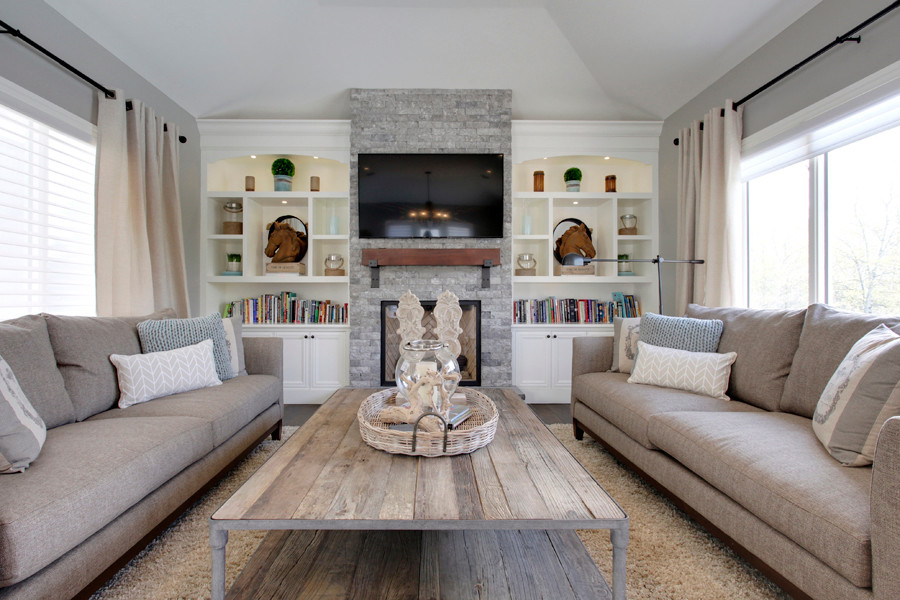 Inspiration pour une salle de séjour traditionnelle ouverte avec un mur gris, un sol en bois brun, une cheminée standard, un manteau de cheminée en pierre et un téléviseur encastré.