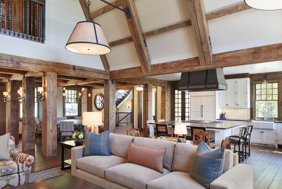 Diseño de sala de estar abierta tradicional grande con suelo de madera en tonos medios, todas las chimeneas, marco de chimenea de piedra, paredes blancas y suelo marrón