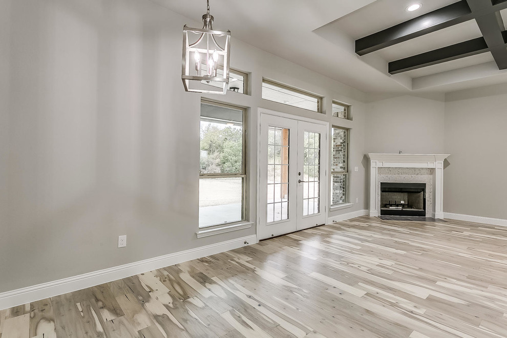 Inspiration for a medium sized modern open plan games room in Dallas with grey walls, light hardwood flooring, a corner fireplace, a tiled fireplace surround, a wall mounted tv and brown floors.