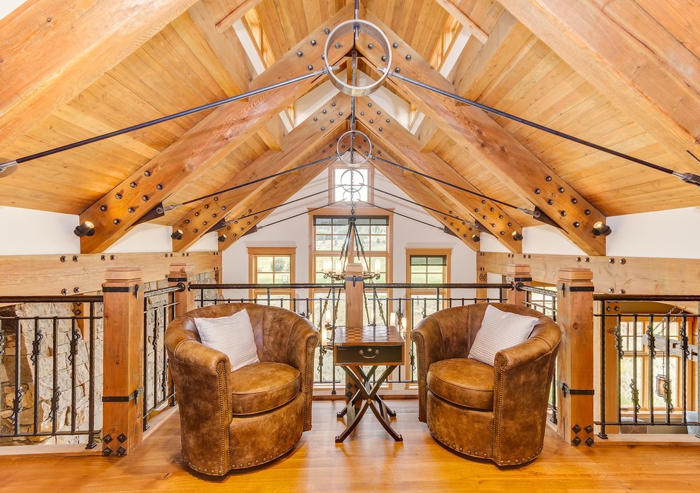 Inspiration for a large rustic loft-style medium tone wood floor family room remodel in Denver with white walls