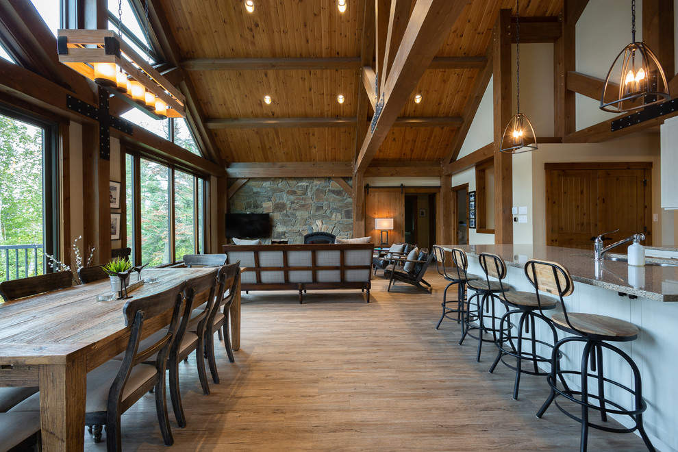 Example of a large mountain style open concept linoleum floor and brown floor family room design in Other with beige walls, a wood stove, a stone fireplace and a wall-mounted tv