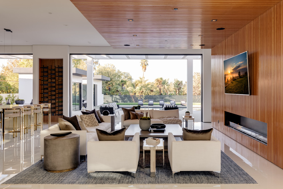 Example of a huge trendy open concept porcelain tile and white floor family room design in Los Angeles with brown walls, a standard fireplace, a wood fireplace surround and a wall-mounted tv
