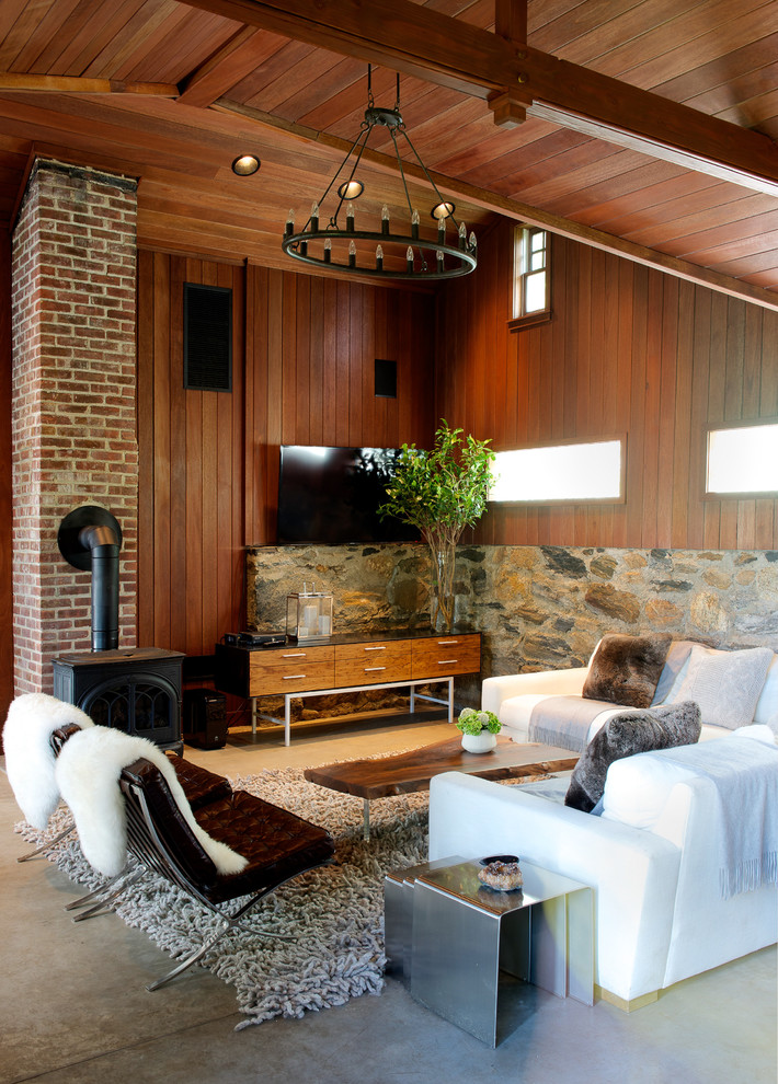 Idées déco pour une salle de séjour contemporaine avec un mur marron, sol en béton ciré, un poêle à bois, un manteau de cheminée en brique et un téléviseur fixé au mur.