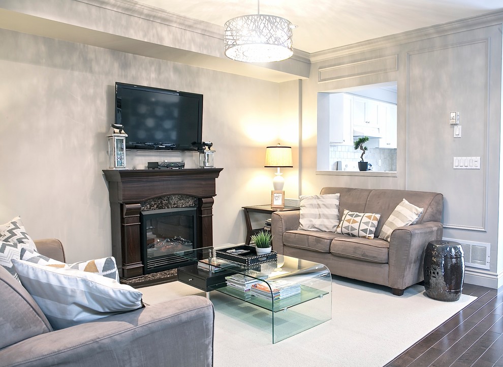 Cette image montre une petite salle de séjour traditionnelle ouverte avec un mur gris, parquet foncé, une cheminée standard et un téléviseur fixé au mur.