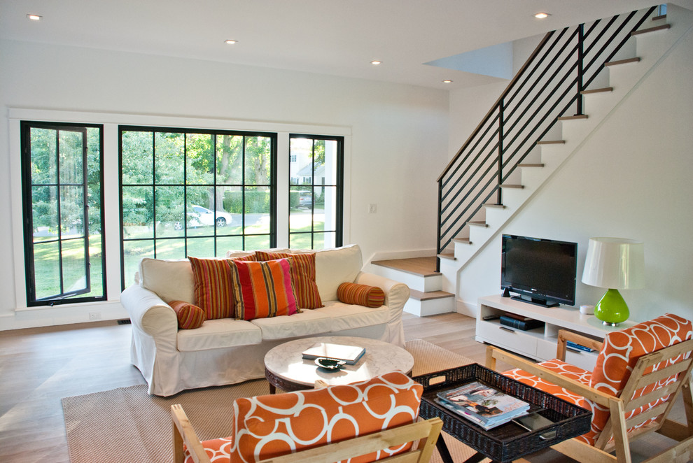 Landhaus Wohnzimmer mit weißer Wandfarbe, braunem Holzboden und freistehendem TV in New York