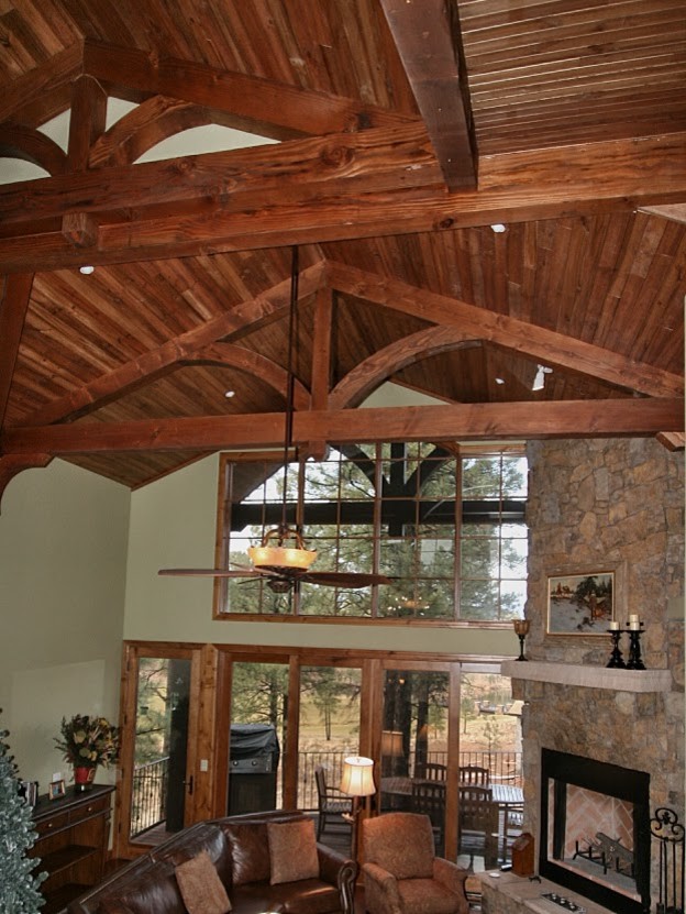 Exemple d'une salle de séjour montagne ouverte avec un sol en bois brun, une cheminée d'angle et un manteau de cheminée en pierre.