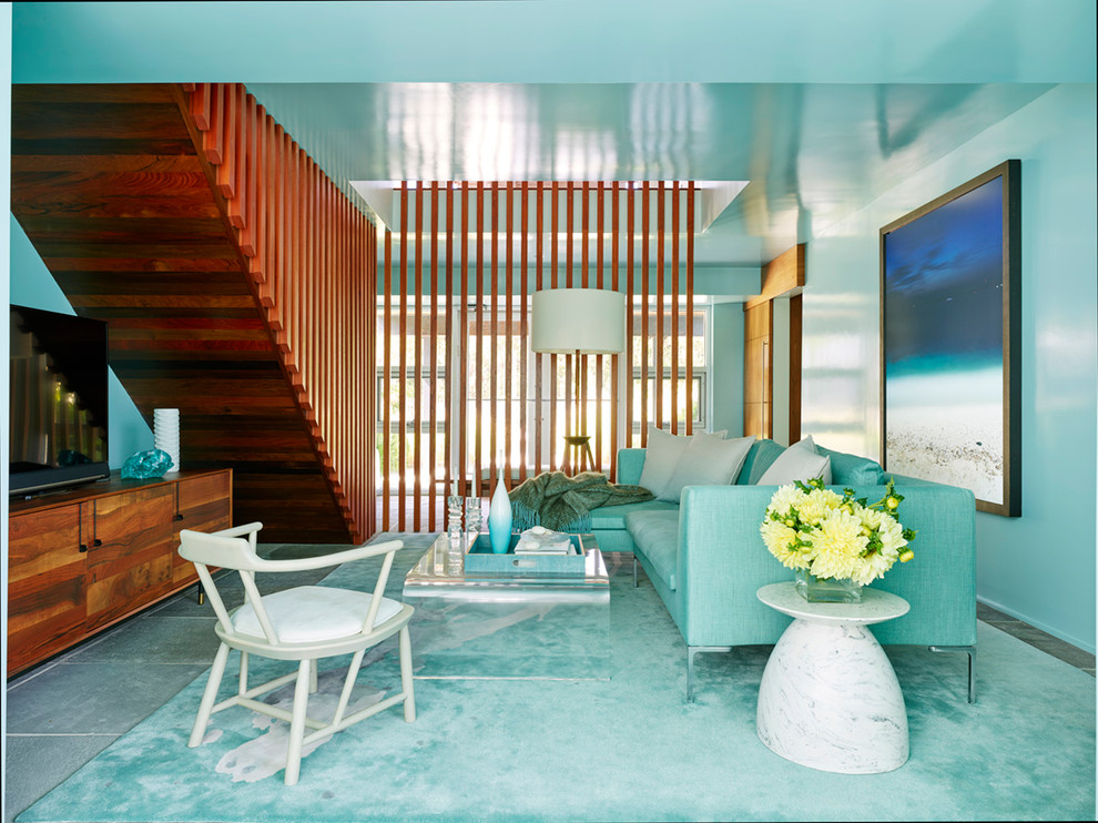 Idée de décoration pour une salle de séjour marine avec un mur bleu, un téléviseur indépendant et un sol gris.
