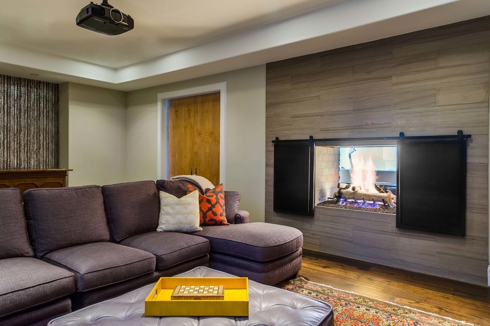 Inspiration pour une salle de séjour design fermée avec un mur gris, un sol en bois brun et une cheminée double-face.