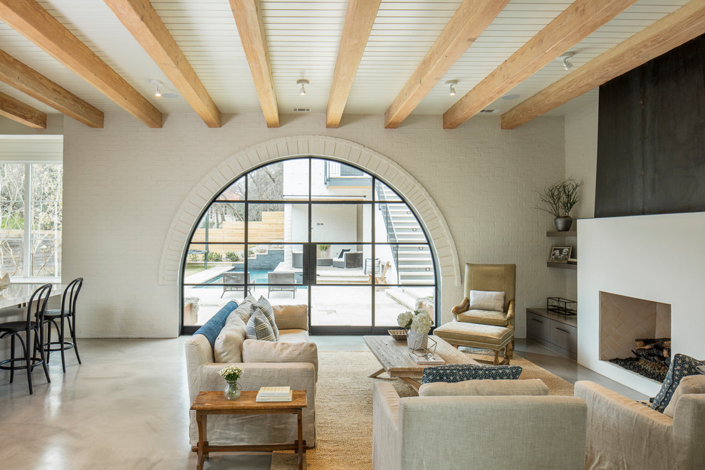 На фото: открытая гостиная комната в стиле неоклассика (современная классика) с белыми стенами, бетонным полом, горизонтальным камином и серым полом с