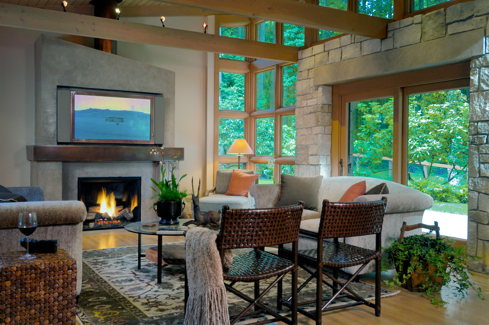 This is an example of a medium sized classic open plan games room in Seattle with light hardwood flooring, a concealed tv, white walls, a standard fireplace, a concrete fireplace surround and brown floors.