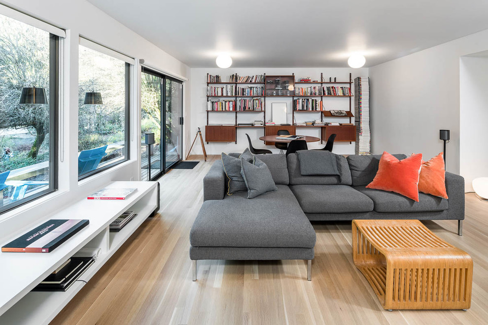 Diseño de sala de estar abierta moderna con paredes blancas, suelo de madera clara y suelo beige