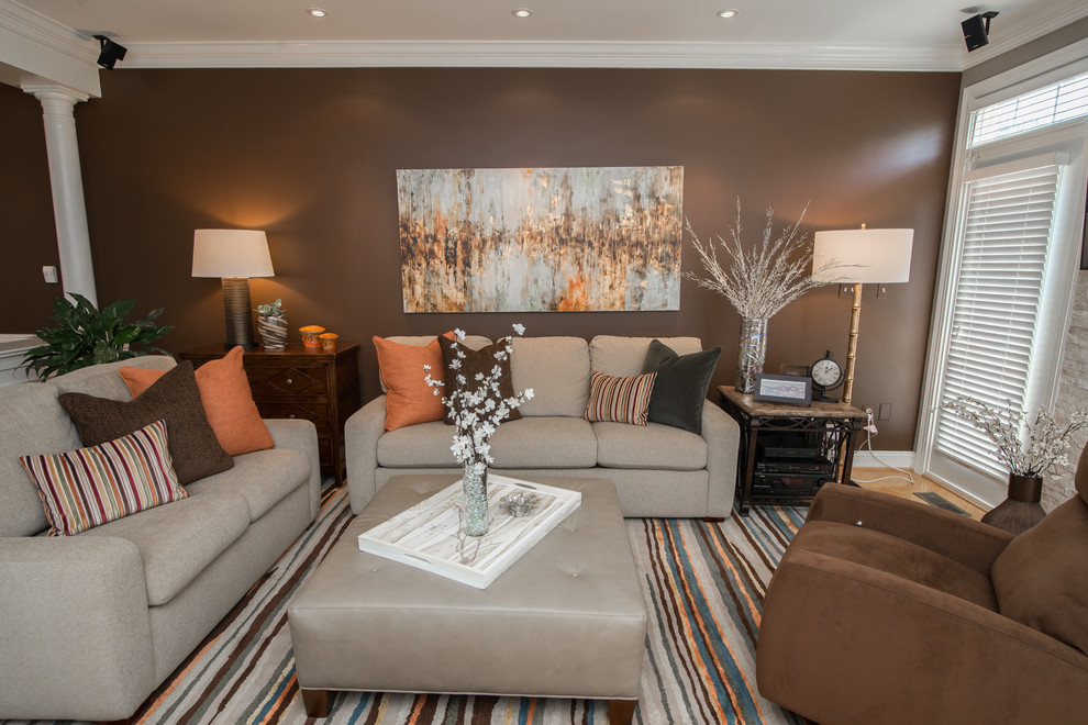 Immagine di un soggiorno tradizionale aperto con pareti marroni, parquet chiaro, TV a parete, camino classico e cornice del camino in pietra