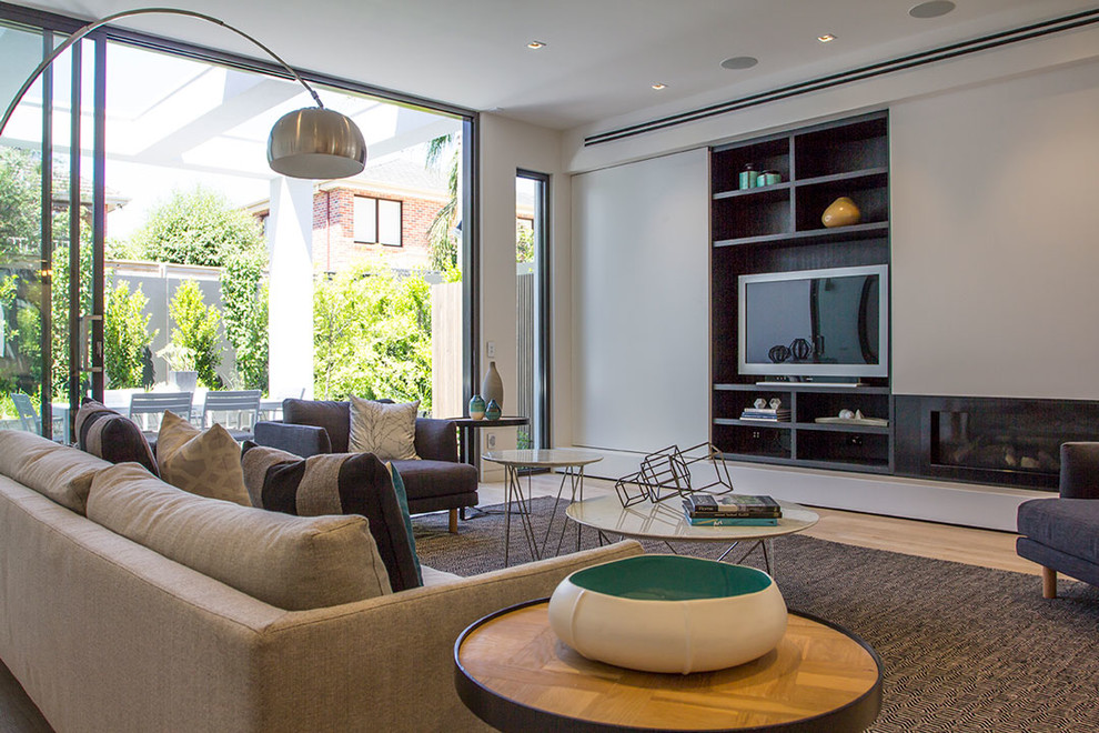 Mittelgroßes, Offenes Modernes Wohnzimmer mit weißer Wandfarbe, hellem Holzboden, Eckkamin, Kaminumrandung aus Metall und Multimediawand in Melbourne