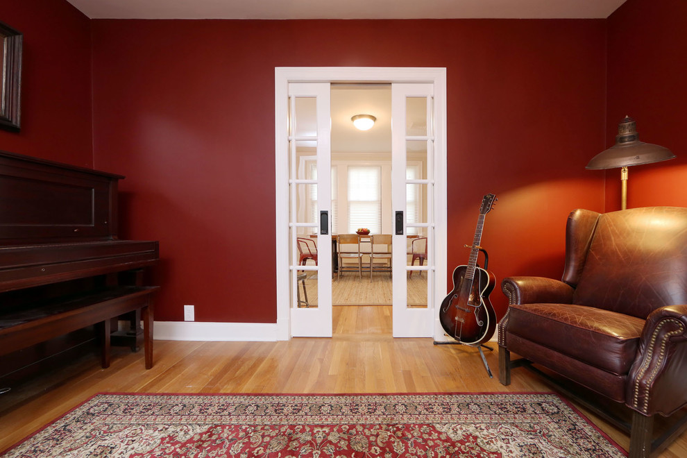 Réalisation d'une salle de séjour bohème de taille moyenne et ouverte avec une salle de musique, un mur rouge et un sol en bois brun.