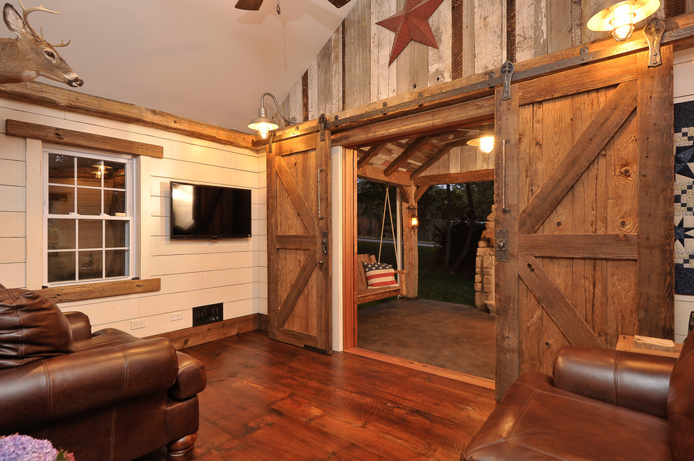 Imagen de sala de estar cerrada rústica de tamaño medio con paredes beige, suelo de madera oscura y televisor colgado en la pared