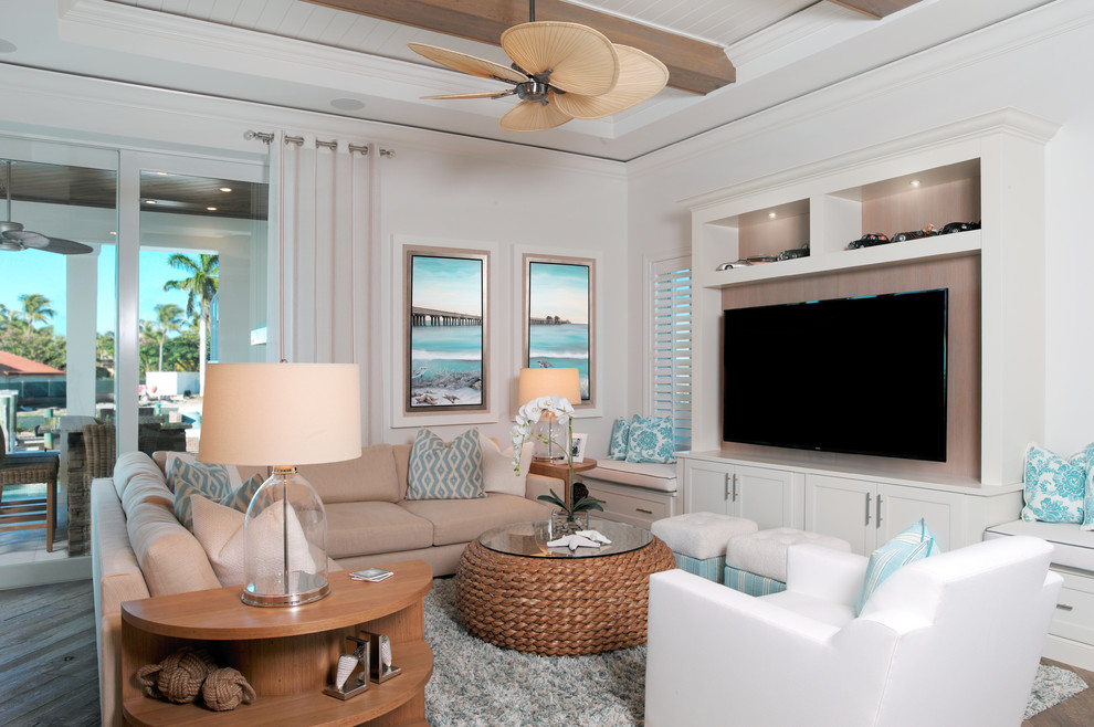 Modelo de sala de estar con barra de bar abierta costera extra grande sin chimenea con paredes blancas, suelo de madera en tonos medios y televisor colgado en la pared