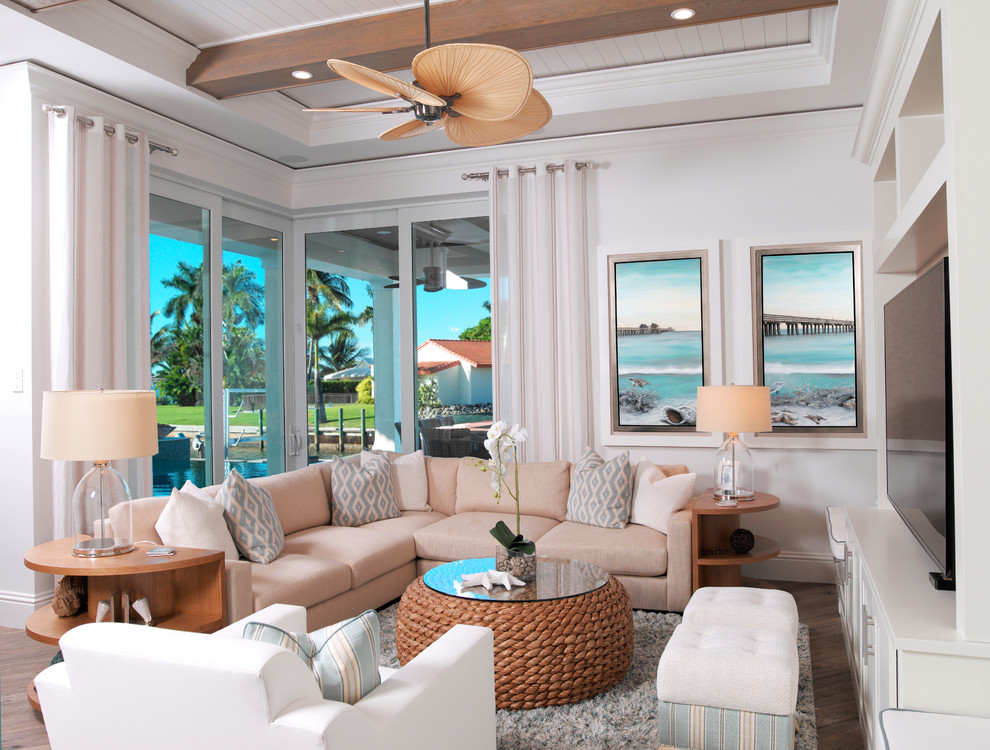 Geräumiges, Offenes Maritimes Wohnzimmer ohne Kamin mit Hausbar, weißer Wandfarbe, braunem Holzboden und TV-Wand in Miami