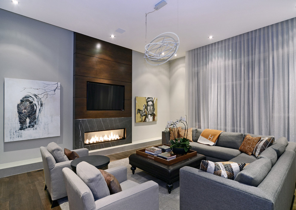 Example of a trendy medium tone wood floor family room design in Calgary with gray walls, a ribbon fireplace, a stone fireplace and a media wall