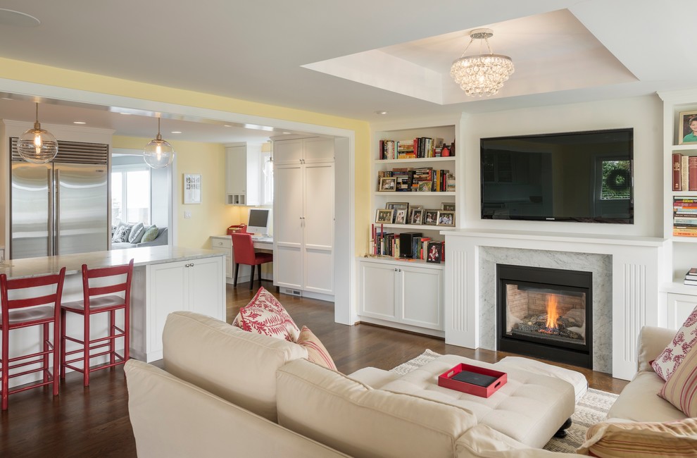 Пример оригинального дизайна: открытая гостиная комната в классическом стиле с желтыми стенами, темным паркетным полом, стандартным камином и телевизором на стене