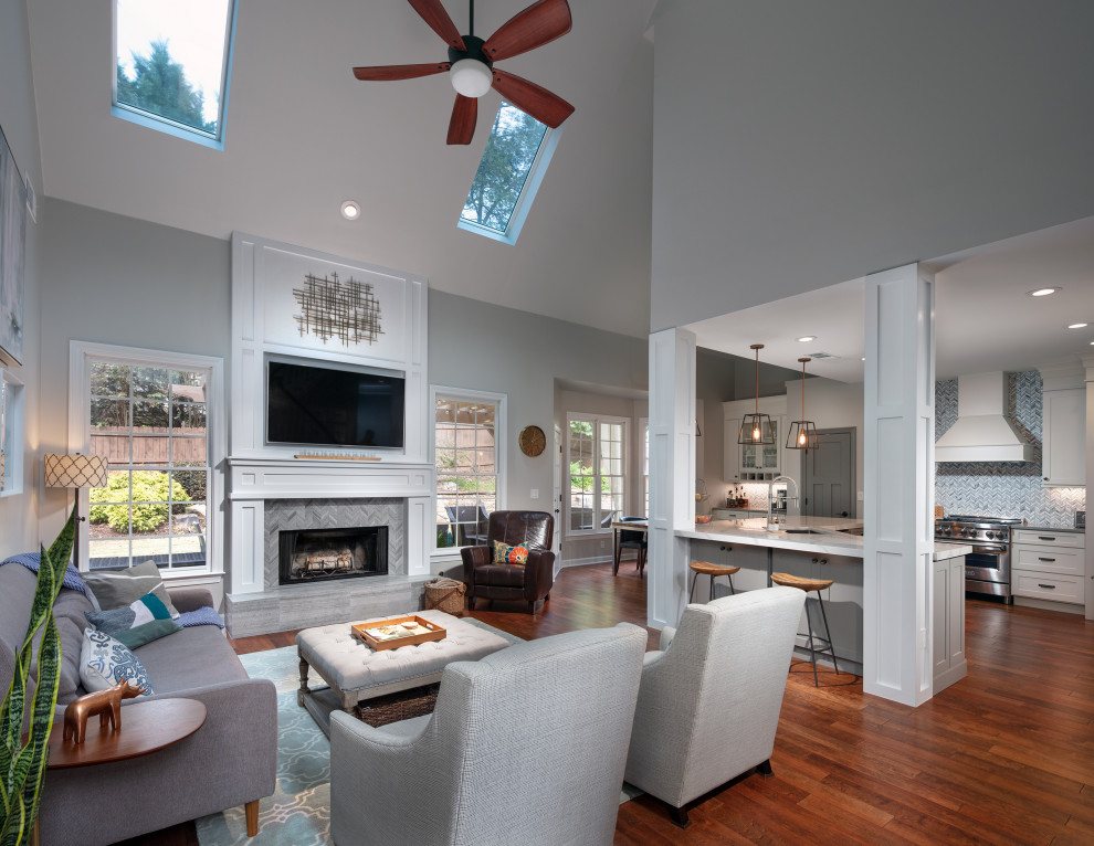 This is an example of a medium sized modern open plan games room in Atlanta with a home bar, grey walls, dark hardwood flooring, a standard fireplace, a tiled fireplace surround, a wall mounted tv, brown floors and a vaulted ceiling.