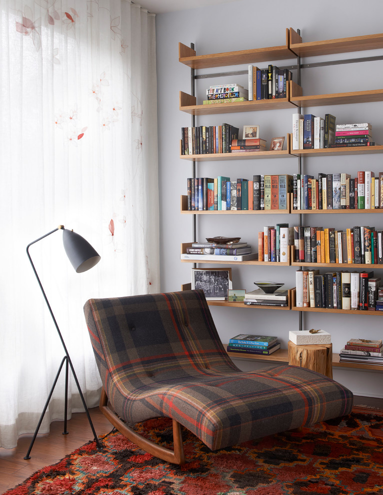 Idée de décoration pour une salle de séjour design avec un sol en bois brun, un sol marron, une bibliothèque ou un coin lecture et un mur blanc.