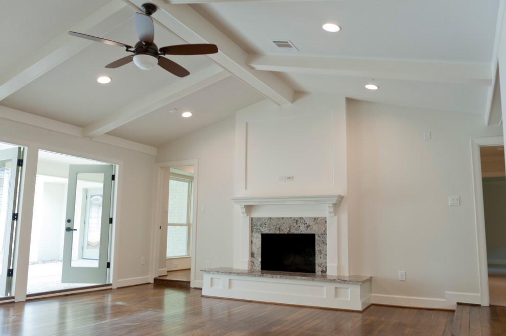 This is an example of a large world-inspired open plan games room in Houston with white walls, medium hardwood flooring, a standard fireplace, a stone fireplace surround and a wall mounted tv.