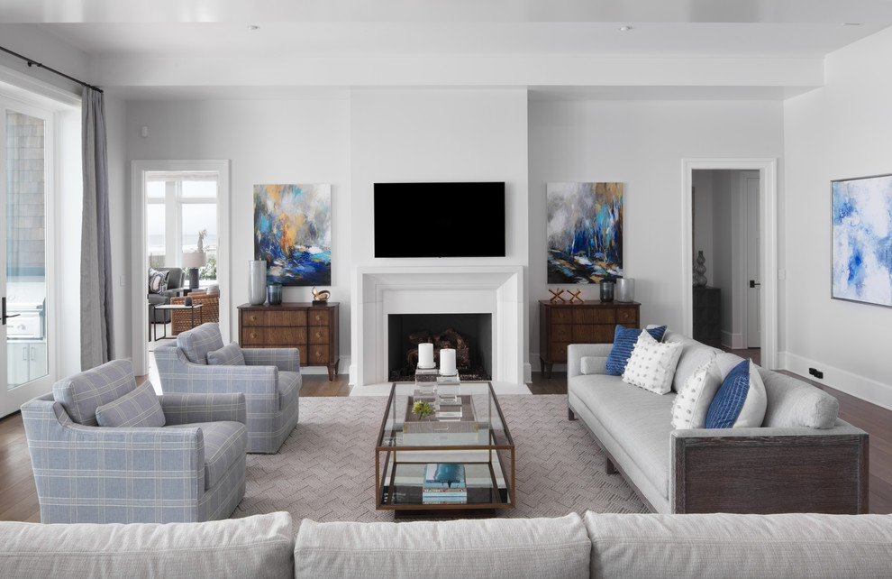 Imagen de sala de estar cerrada marinera con paredes blancas, suelo de madera oscura, todas las chimeneas, televisor colgado en la pared y alfombra