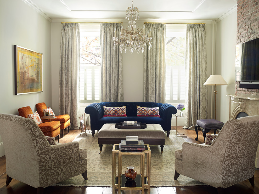 Offenes Klassisches Wohnzimmer mit TV-Wand, beiger Wandfarbe, braunem Holzboden, Kamin und Kaminumrandung aus Stein in New York