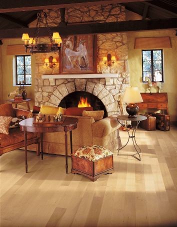 Modelo de sala de estar abierta tradicional de tamaño medio con paredes amarillas, suelo de madera clara, todas las chimeneas y marco de chimenea de piedra