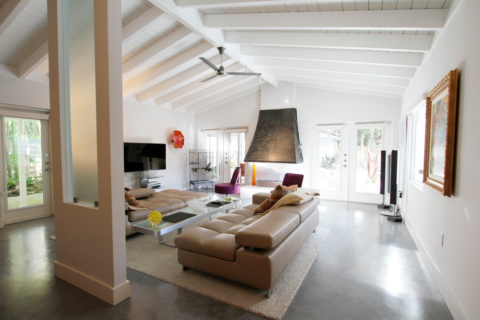Ispirazione per un grande soggiorno minimalista aperto con pareti bianche, pavimento in cemento, camino bifacciale, TV a parete e pavimento grigio
