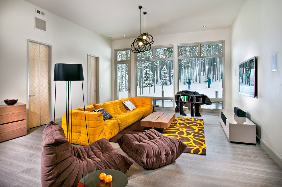 Modelo de sala de estar abierta contemporánea grande sin chimenea con televisor colgado en la pared, paredes grises, suelo de madera clara, suelo gris y alfombra