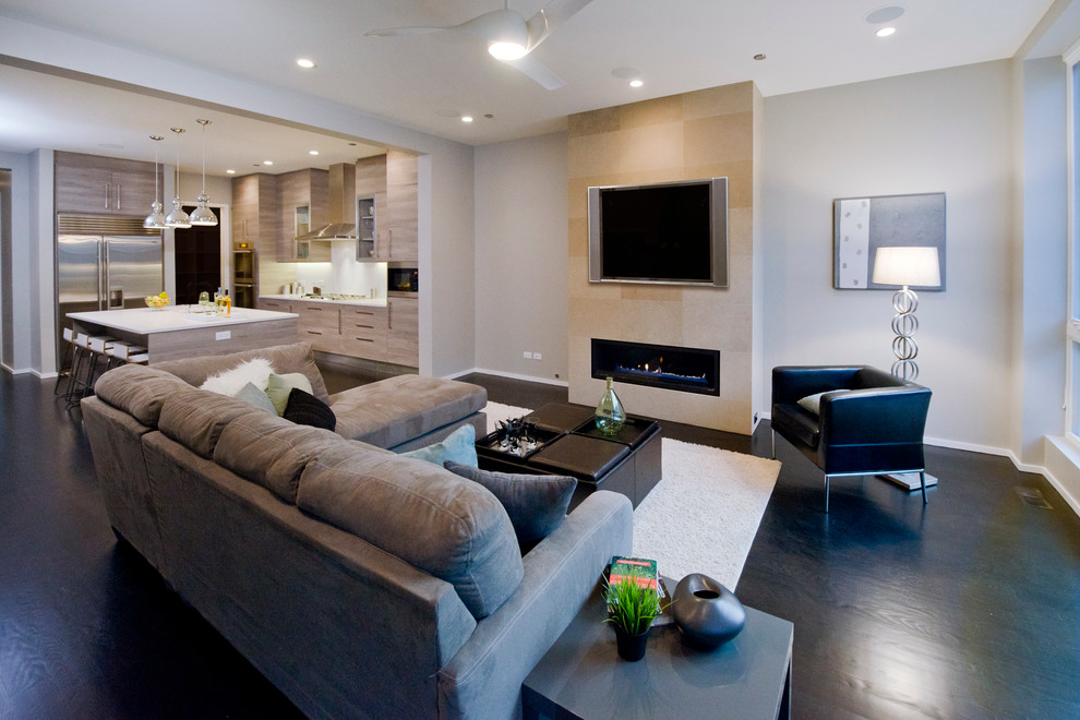 На фото: открытая гостиная комната среднего размера:: освещение в стиле модернизм с серыми стенами, темным паркетным полом, стандартным камином, фасадом камина из камня и телевизором на стене с