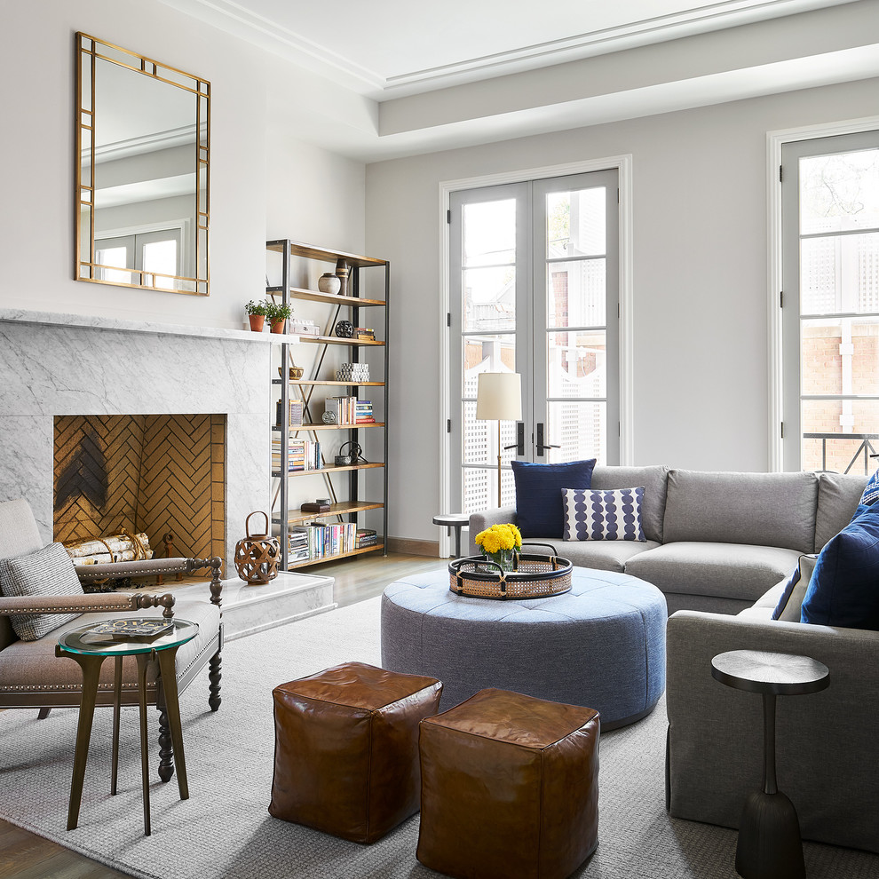 Cette photo montre une salle de séjour chic avec une bibliothèque ou un coin lecture, un mur blanc, un sol en bois brun, une cheminée standard et un sol marron.