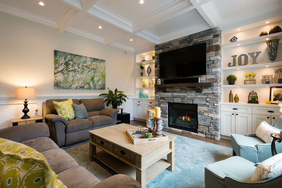 Imagen de sala de estar abierta clásica grande con paredes grises, suelo de madera en tonos medios, todas las chimeneas, marco de chimenea de piedra, pared multimedia y alfombra