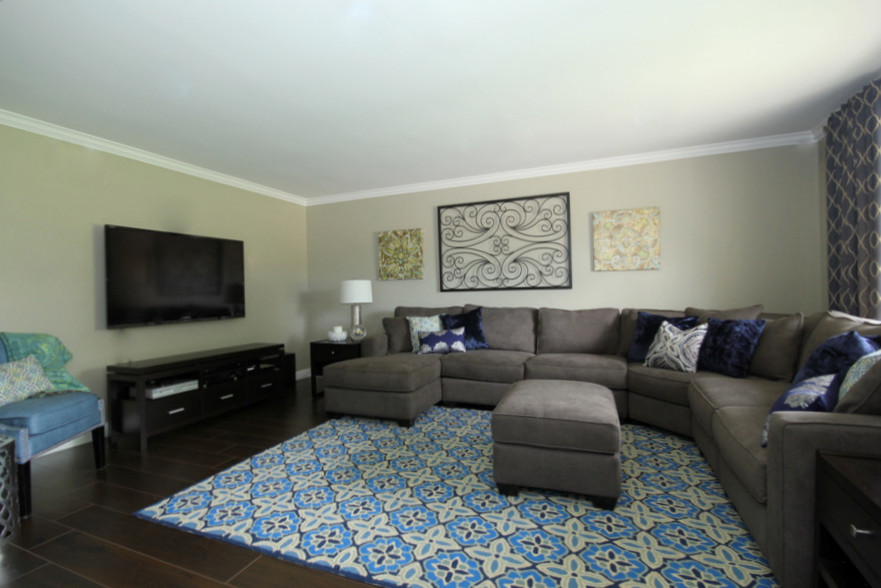 Foto de sala de estar cerrada tradicional renovada de tamaño medio sin chimenea con paredes beige, suelo de madera en tonos medios y televisor colgado en la pared