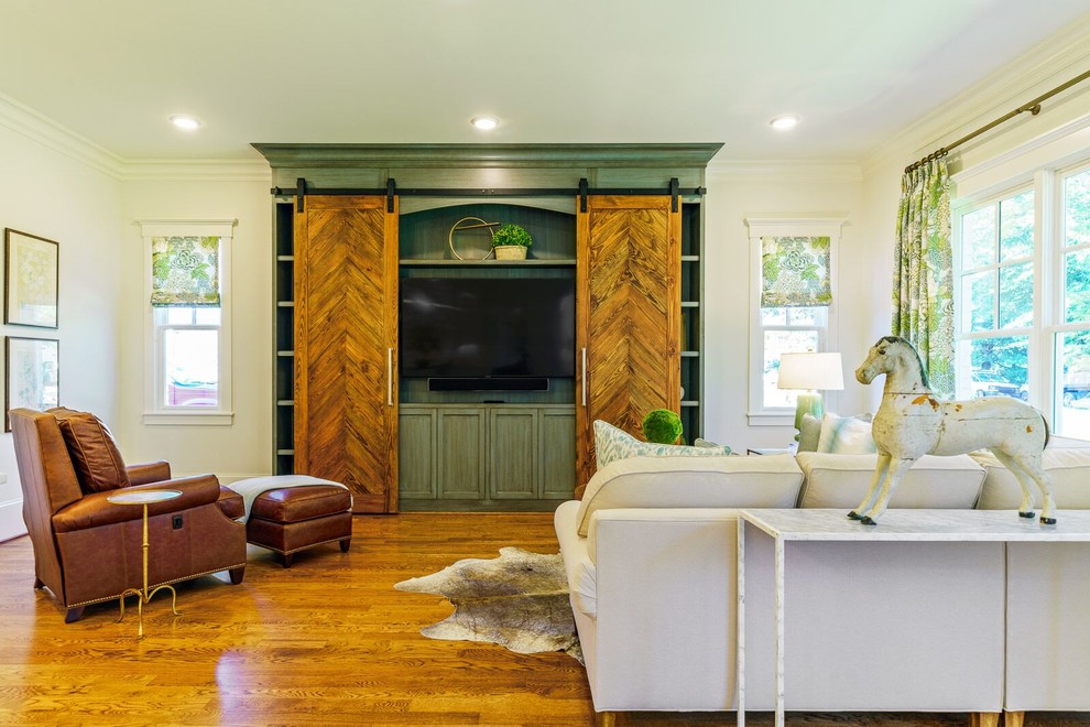 Ejemplo de sala de estar abierta campestre de tamaño medio con paredes blancas, suelo de madera en tonos medios, televisor retractable y suelo marrón