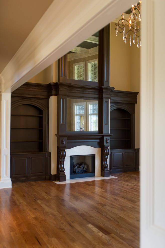Imagen de sala de estar clásica extra grande sin televisor con paredes beige, suelo de madera en tonos medios, todas las chimeneas y marco de chimenea de madera