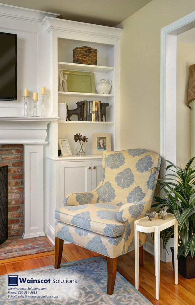 Diseño de sala de estar con biblioteca abierta mediterránea de tamaño medio con paredes beige, suelo de madera clara, marco de chimenea de ladrillo y televisor colgado en la pared