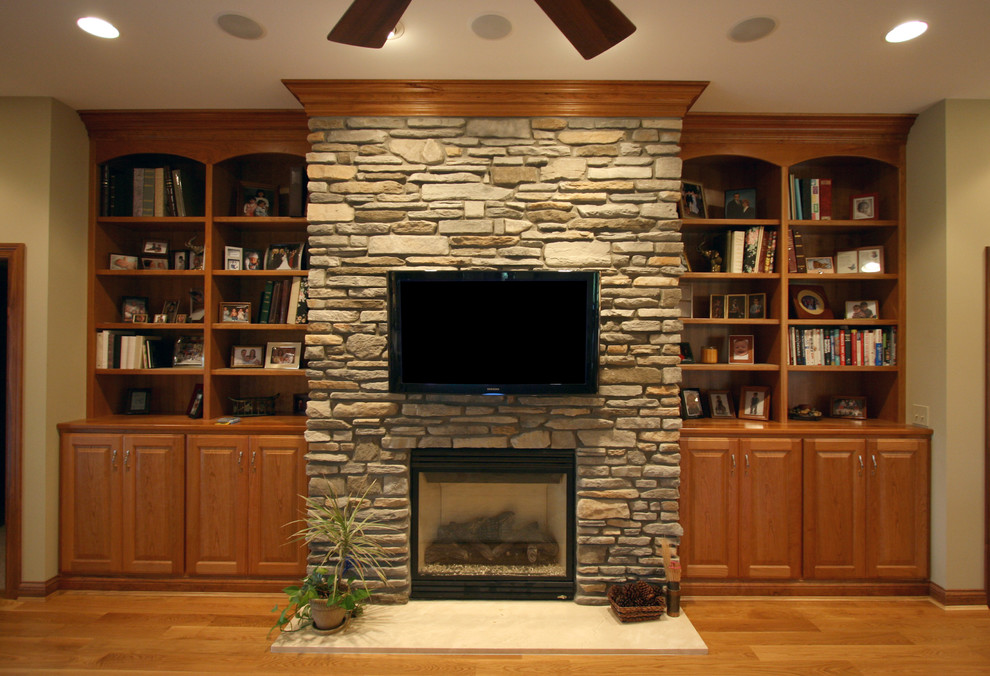 Ejemplo de sala de estar abierta clásica pequeña con paredes beige, suelo de madera clara, todas las chimeneas, marco de chimenea de piedra y televisor colgado en la pared