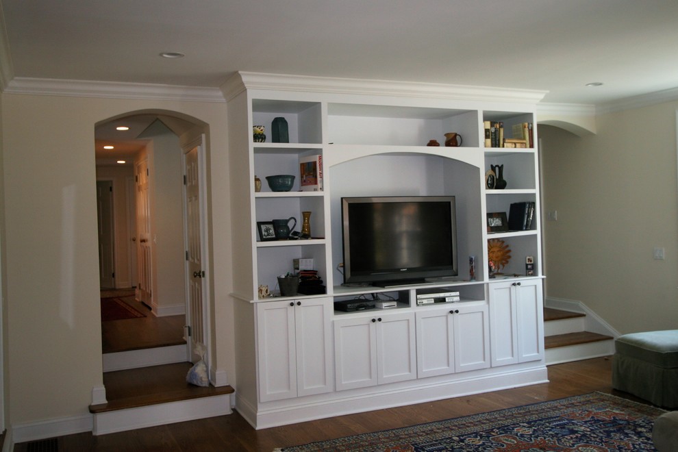 Mittelgroßes, Abgetrenntes Klassisches Wohnzimmer ohne Kamin mit beiger Wandfarbe, dunklem Holzboden, freistehendem TV und braunem Boden in New York