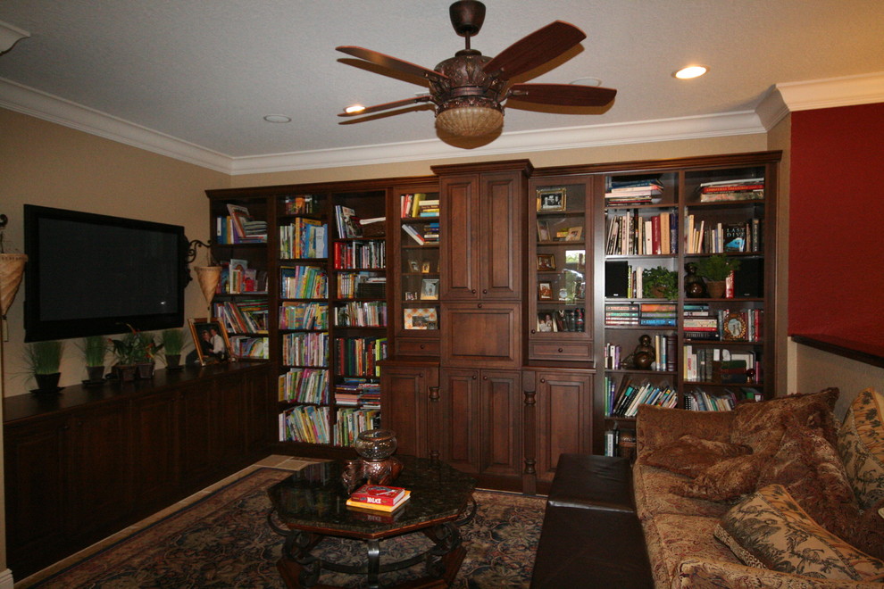 Foto di un soggiorno tradizionale di medie dimensioni e chiuso con libreria, pareti beige, pavimento in travertino, nessun camino e parete attrezzata
