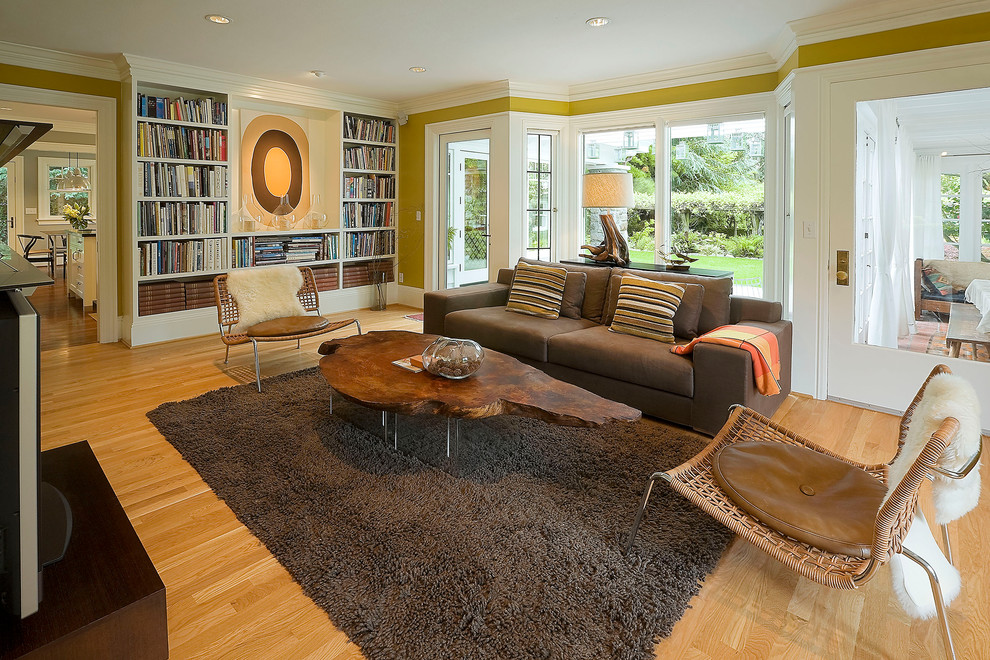 Imagen de sala de estar abierta tradicional con paredes amarillas y suelo de madera en tonos medios
