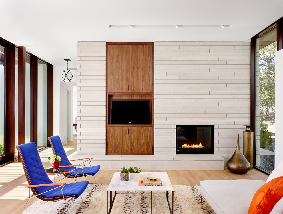 Источник вдохновения для домашнего уюта: гостиная комната в современном стиле с белыми стенами, паркетным полом среднего тона, стандартным камином, фасадом камина из плитки, телевизором на стене и ковром на полу
