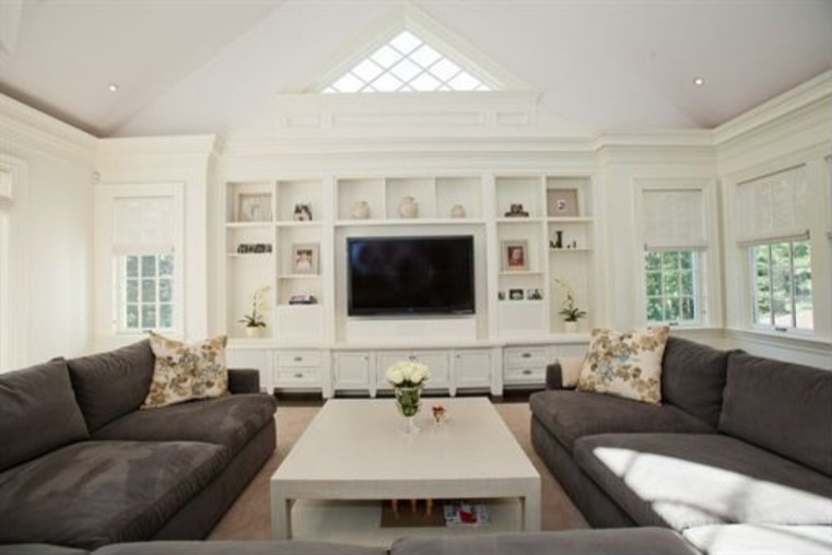 Modelo de sala de estar cerrada tradicional de tamaño medio con paredes blancas, suelo de madera oscura y pared multimedia